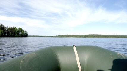 View from a motor boat. The boat floats on the lake, ripples on the water. The sun reflects off the...