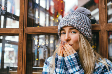Young beautiful blonde girl blows and rubs her hands in the cold winter weather.