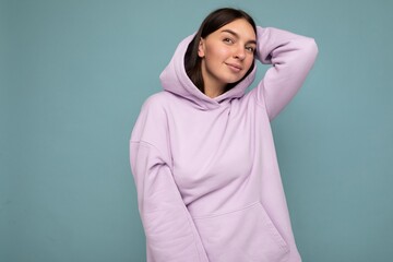Fototapeta premium Young cool happy pretty brunet woman with sincere emotions isolated on background wall with copy space wearing casual purple hoodie. Positive concept