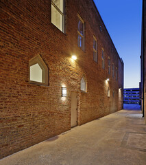 Fototapeta na wymiar Empty alleyway along lit brick building at sunset