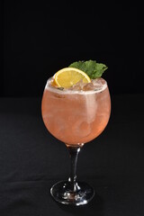 refreshing alcoholic drink with berries, ice vodka and gin, lemon peel served in glass cup on the counter on blurred background