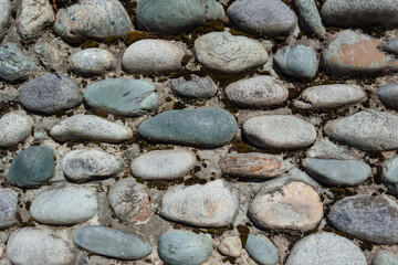 A close-up of a wall made of stones with moss. Textured background