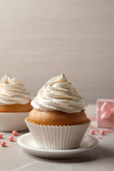 Delicious cupcakes decorated with cream on light grey table