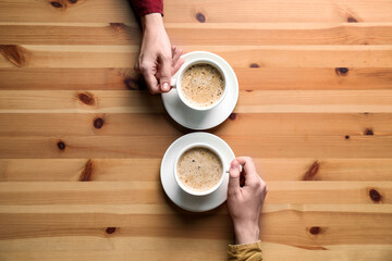 Women with cups of coffee at wooden table, top view