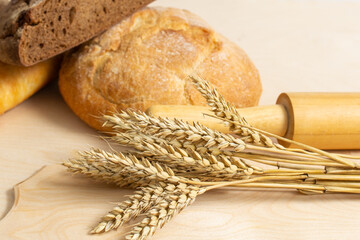 Fresh homemade bread with wheat ears, close-up and rolling pin.