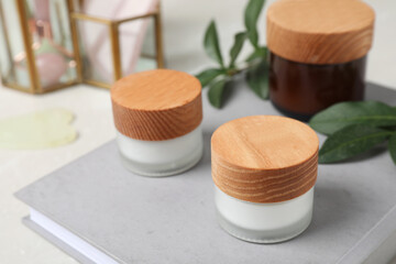 Jars of cream on grey book, closeup
