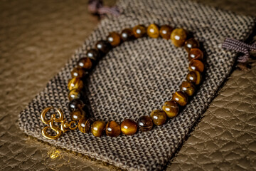 on the golden surface on a linen bag there is a bracelet made of natural stones