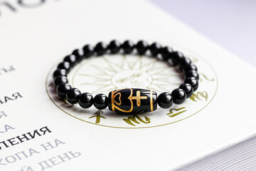 on the paper surface with astrological symbols is a bracelet made of natural stone beads