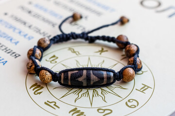 on the paper surface with astrological symbols is a bracelet made of natural stone beads