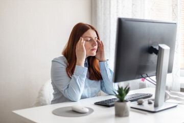 Young Caucasian women are stressed and tired from work at a white desk with a computer at home