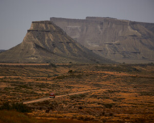 desert landscape of navarra, sandy plains under the sun and roads towards the horizon with mountains in the background 