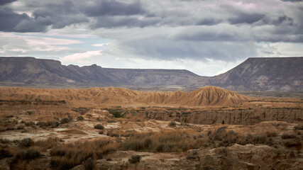 desert landscape of navarra, sandy plains under the sun and roads towards the horizon with mountains in the background 