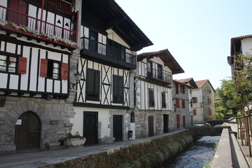 Fototapeta na wymiar Typical colorful Basque houses with a canal with water passing in front of the street, in Lesaka