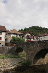 Fototapeta na wymiar Stone bridge over a river and typical houses with a cloudy sky in Otsagabia, Navarra