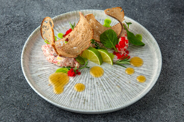 Crab meat pate with caviar, bread chips and citrus. Ready menu for the restaurant. Neutral gray blue textured background