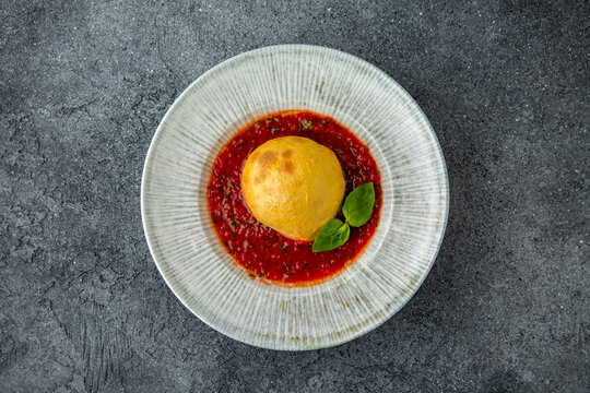 Baked burrata in tomato sauce. Ready menu for the restaurant. Neutral gray blue textured background.