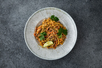 Thai soba with veal vegetables and sesame seeds. Ready menu for the restaurant. Neutral gray blue textured background