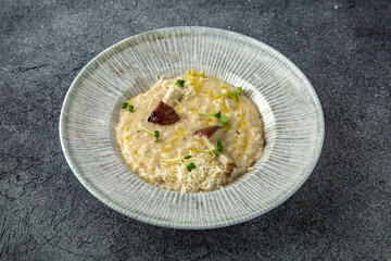 Risotto in a creamy sauce with mushrooms and parmesan. Ready menu for the restaurant. Neutral gray blue textured background