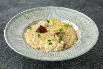 Risotto in a creamy sauce with mushrooms and parmesan. Ready menu for the restaurant. Neutral gray blue textured background
