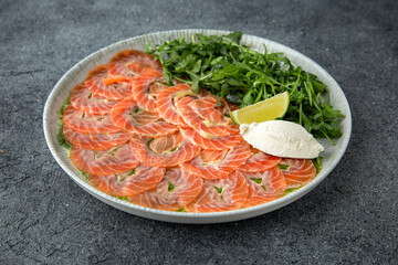 Salmon carpaccio with cheese and arugula. Ready menu for the restaurant. Gray blue textured background