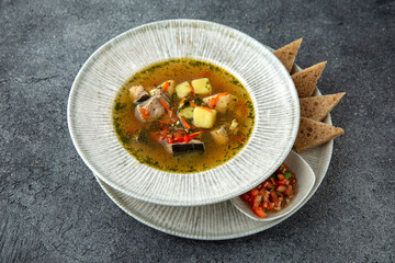 First course. Chicken soup with vegetables and pieces of meat. Ready menu for the restaurant. Neutral gray blue textured background