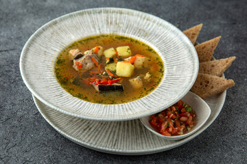 First course. Chicken soup with vegetables and pieces of meat. Ready menu for the restaurant. Neutral gray blue textured background