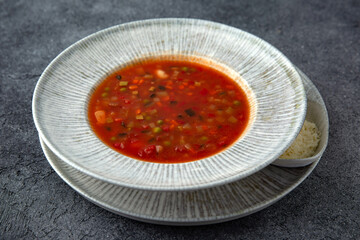 First course, soup with vegetables, in meat broth. Ready menu for the restaurant. Neutral gray blue textured background