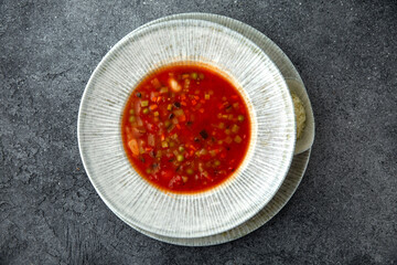 First course, soup with vegetables, in meat broth. Ready menu for the restaurant. Neutral gray blue textured background