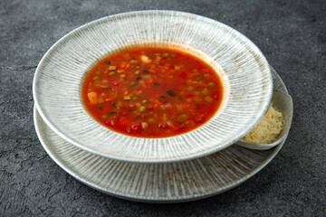 First course, soup with vegetables, in meat broth. Ready menu for the restaurant. Neutral gray blue textured background