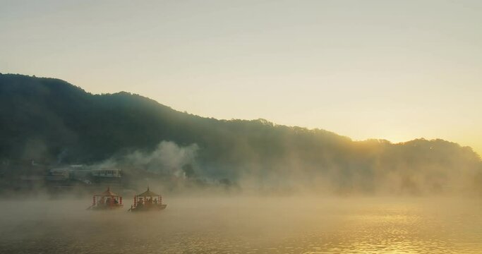 Traditional Chinese style boat on river lake with fog misty in the morning and sunlight sunrise hill on background at Ban Rak Thai village, Mae hong son, Thailand