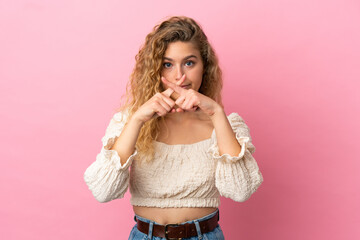 Young blonde woman isolated on pink background showing a sign of silence gesture