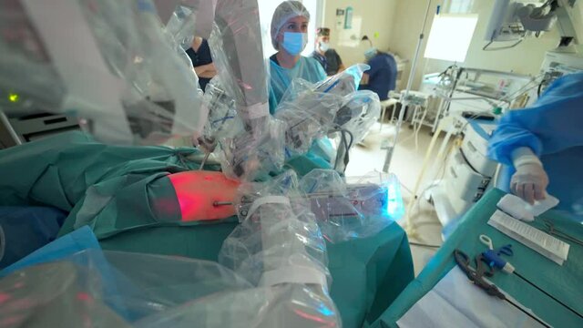 Surgical process with medical robot. Robotic equipment during operation on a patient in clinic. Red light on patient's belly during robotic surgery.