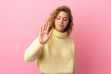 Young blonde woman isolated on pink background making stop gesture and disappointed