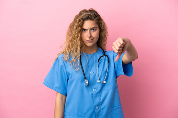 Young surgeon doctor woman isolated on pink background showing thumb down with negative expression © luismolinero