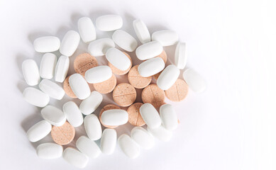 Fototapeta na wymiar White and colored pills on a white background. Oblong and round pills close-up. Healthcare and medicine. 