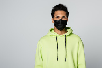 Fototapeta premium african american man in green hoodie and black medical mask isolated on grey
