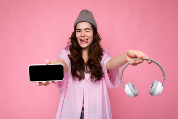 Photo of sexy pretty positive young brunette curly woman wearing pink shirt and grey hat isolated...
