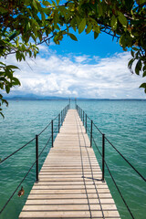 wooden footbridge leads onto the turquoise Garda Lake