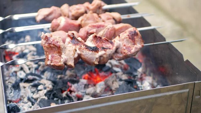 Pork meat on metal skewers. Barbecue with coals for cooking baked food in the fresh air. Outdoor, the backyard of the house. fatty meat is fried on a fire, dripping juice. appetizing