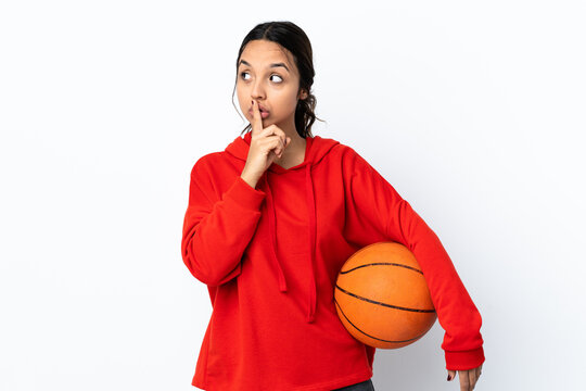Young woman playing basketball over isolated white background showing a sign of silence gesture putting finger in mouth