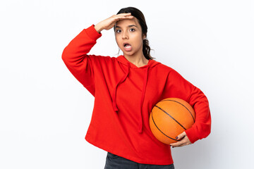 Young woman playing basketball over isolated white background doing surprise gesture while looking to the side