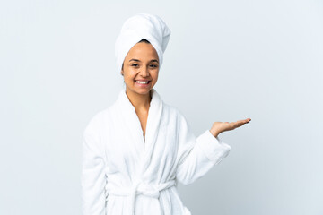 Young woman in bathrobe over isolated white background holding copyspace imaginary on the palm to insert an ad