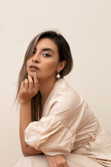 young woman with long straight hair is posing in a relaxed way, wearing makeup and a pink robe, lifestyle and beauty in studio