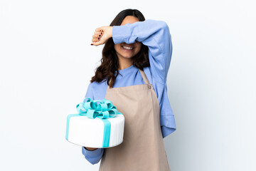 Pastry chef holding a big cake over isolated white background covering eyes by hands