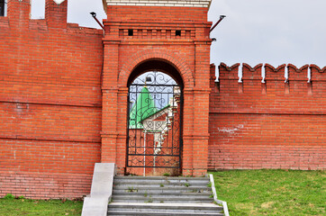 A high red brick fence with carved gates and stairs to the gate. High quality photo