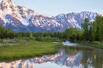 Grand Teton mountains above grassy valley and Snake River in early morning light © Daniel Thornberg