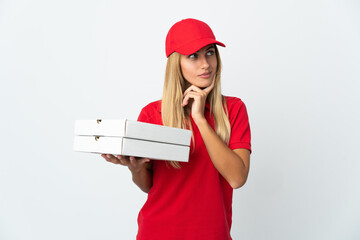 Pizza delivery woman holding a pizza isolated on white background having doubts and thinking