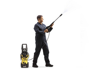 Full length shot of a male worker in a uniform spraying with a pressure washer machine