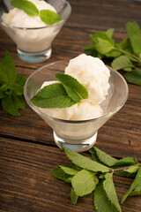 Glass bowl with delicious ice cream and mint leaves.