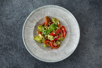 Hearty dietary salad made from tomatoes, avocado, pine nuts and sauce. Vegetarian food. Ready menu for the restaurant. Neutral gray blue textured background